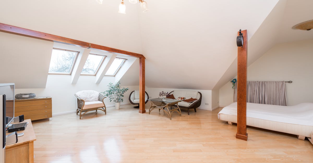 Spacious apartment interior with bed near armchairs and couch next to table and windows near cabinet under chandelier