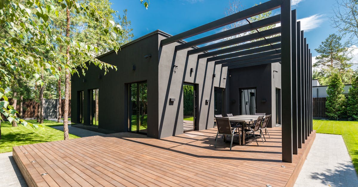 Stylish outdoor space with wooden deck and dining set, surrounded by lush greenery.